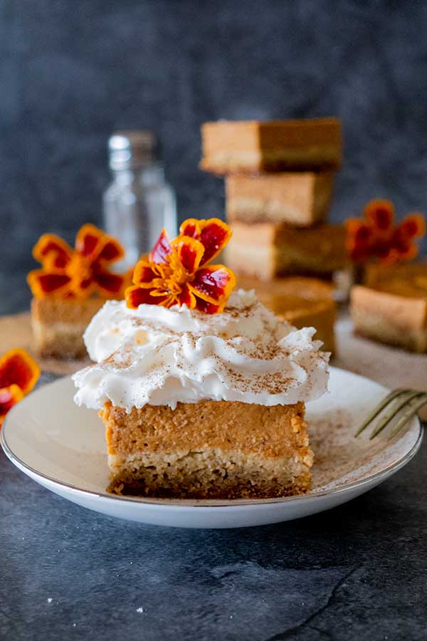 grain-free pumpkin pie bar topped with whipped cream and edible flower on a dessert plate