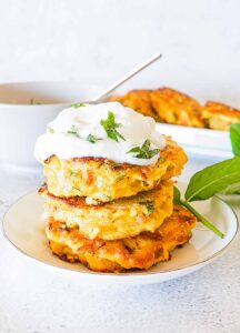 3 stacked salmon burgers on a plate with a cream topping