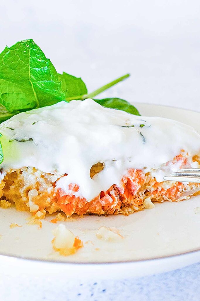sliced salmon burger topped with yogurt on a plate