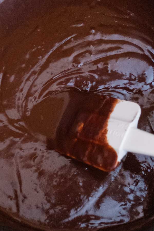 stirring chocolate ganache in a bowl with a spatula