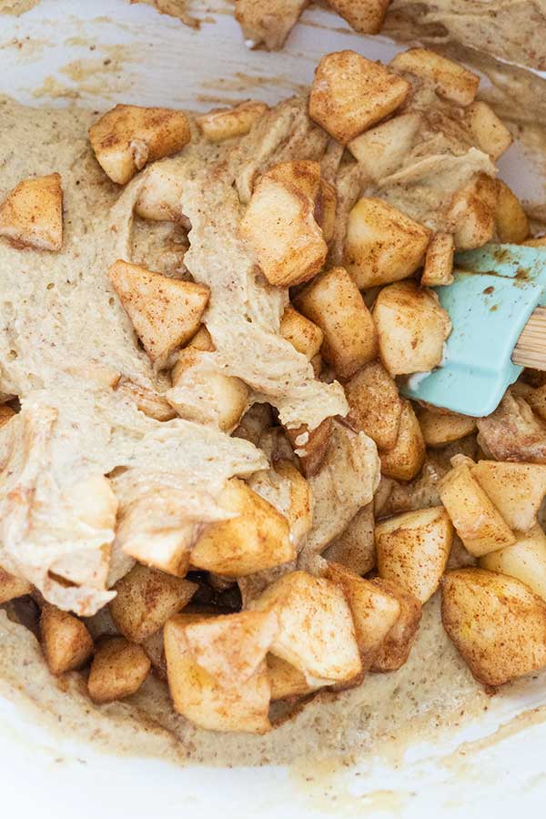 mixing chopped apples with batter in a bowl with a spatula