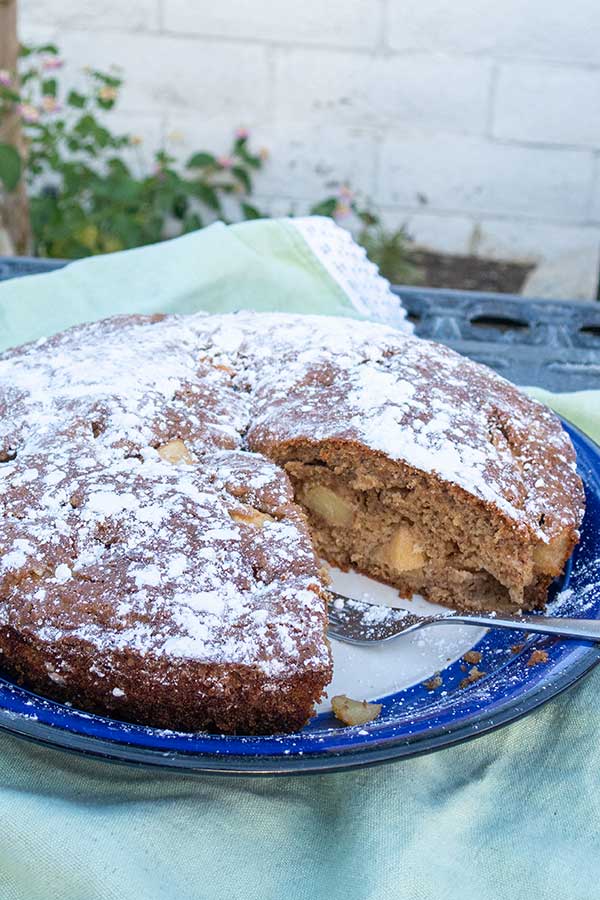 a slice missing from french apple cake in a baking dish