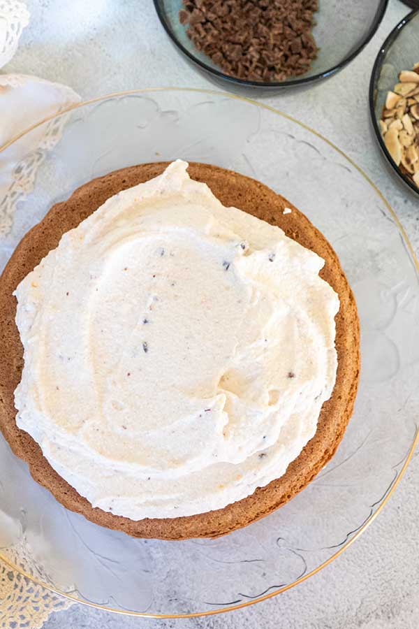 ricotta frosting spread over bottom layer of a round cake