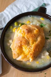 chicken pot pie soup in a bowl topped with a biscuit