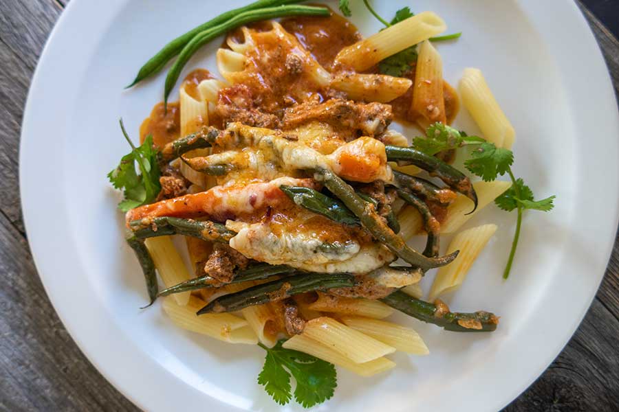 cheesy ground beef with french beans on a plate with pasta