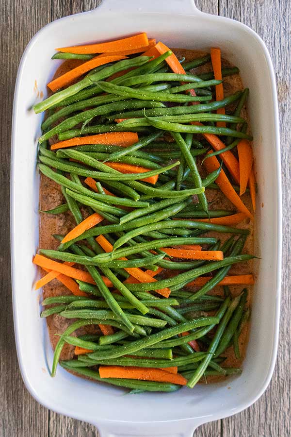 saucy ground beef topped with French beans and carrots in a casserole dish