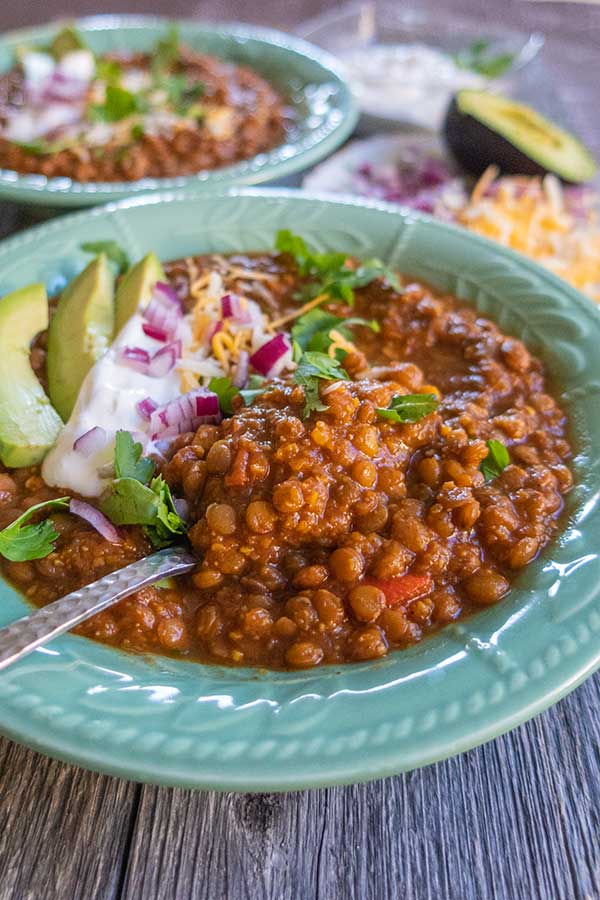 vegetarian lentil chilli with avocado and sour cream in a bowl