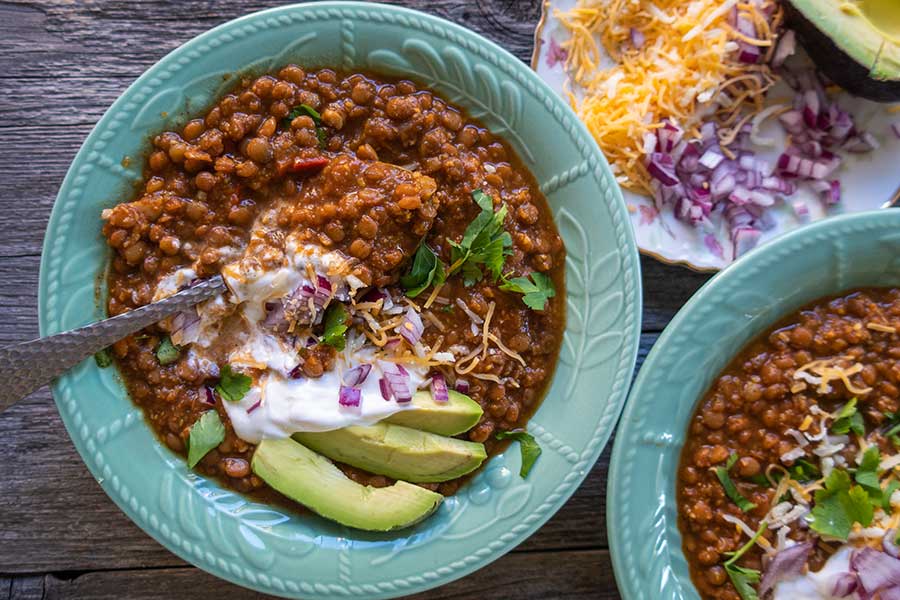 vegetarian lentil chili in a bowl topped with avocado slices 