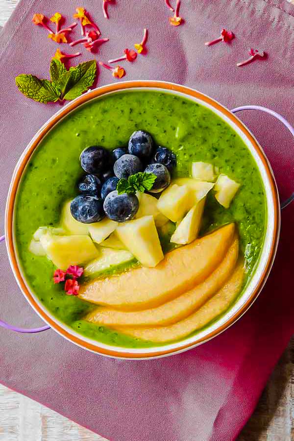 green smoothie bowl topped with fresh fruit