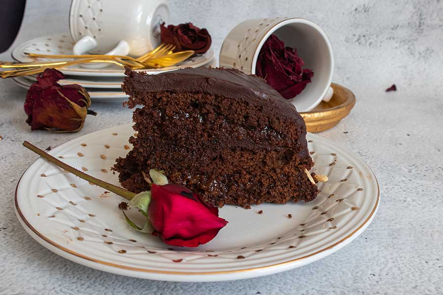 a slice of sacher torte on a dessertt plate with a red rose