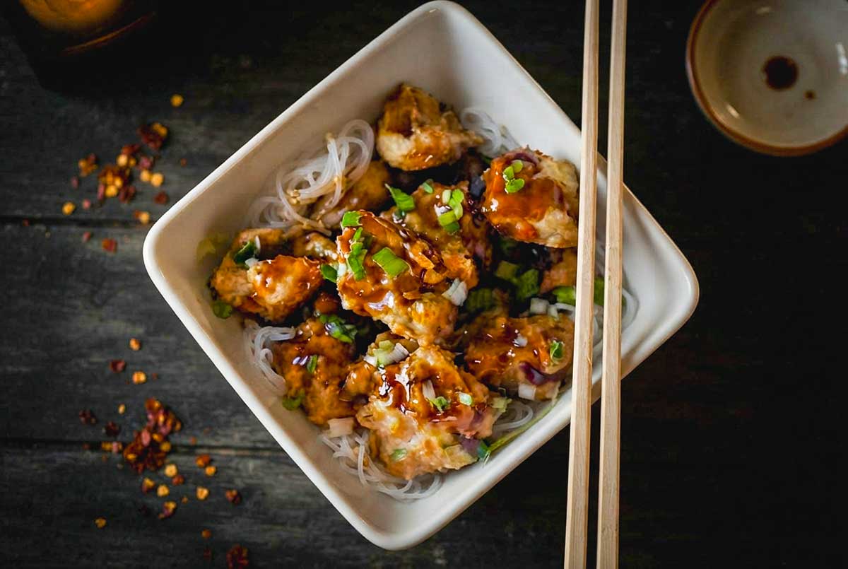 Gluten-Free Asian Chicken Meatballs with Sticky Sauce over rice noodles in a bowl