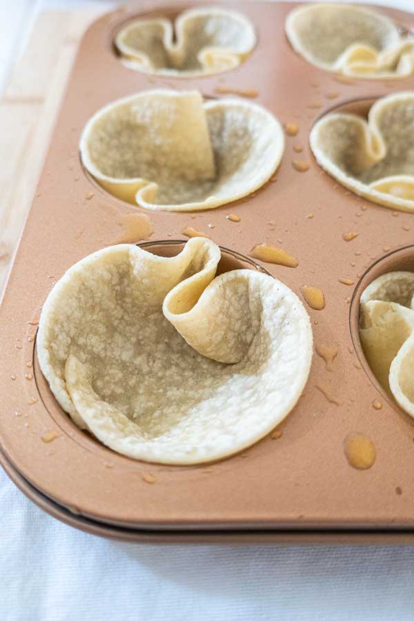 tortillas formed into cups in a muffin pan