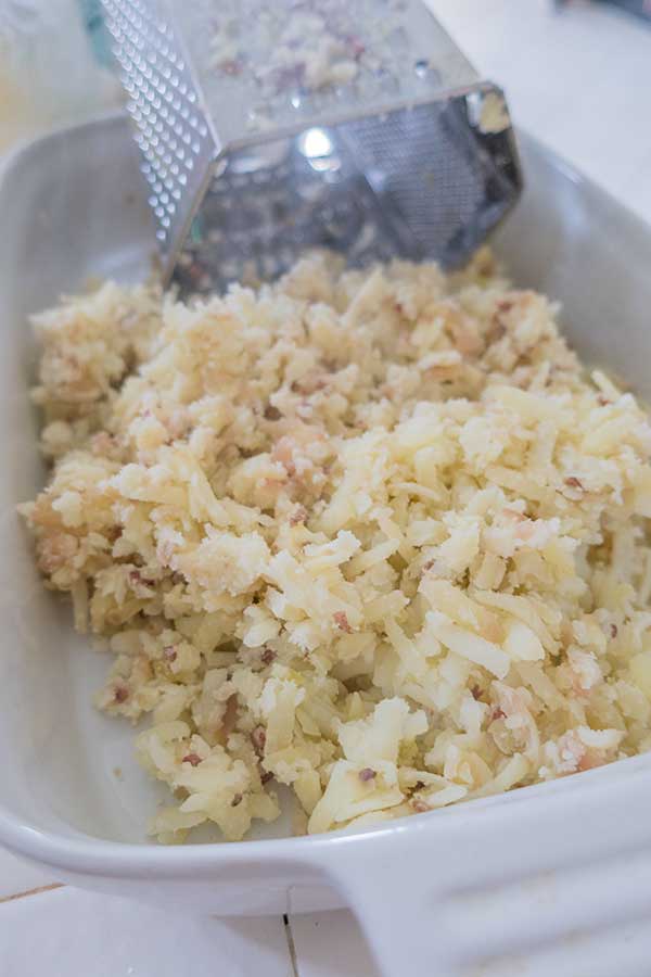 grated cooked potatoes in a bowl with a grater