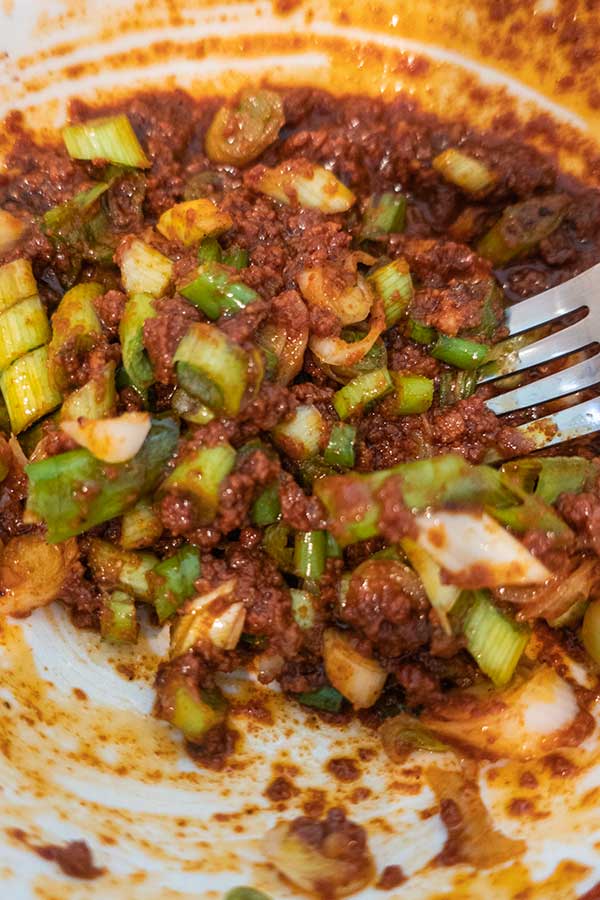 cooked sausage with sliced green onions in a bowl