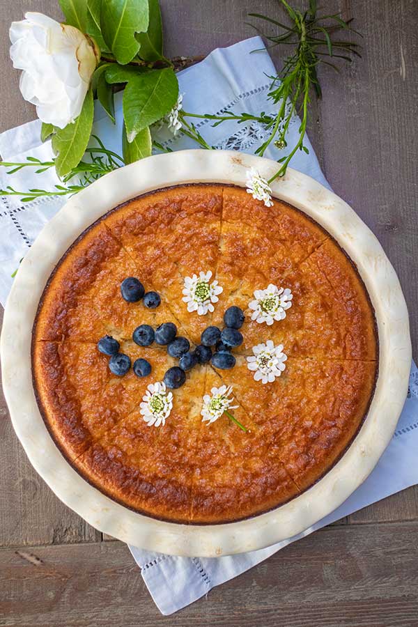 top view of baked coconut pie topped with blueberries and flowers