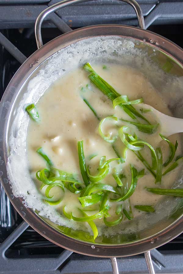 cheese sauce with green onions in a pot