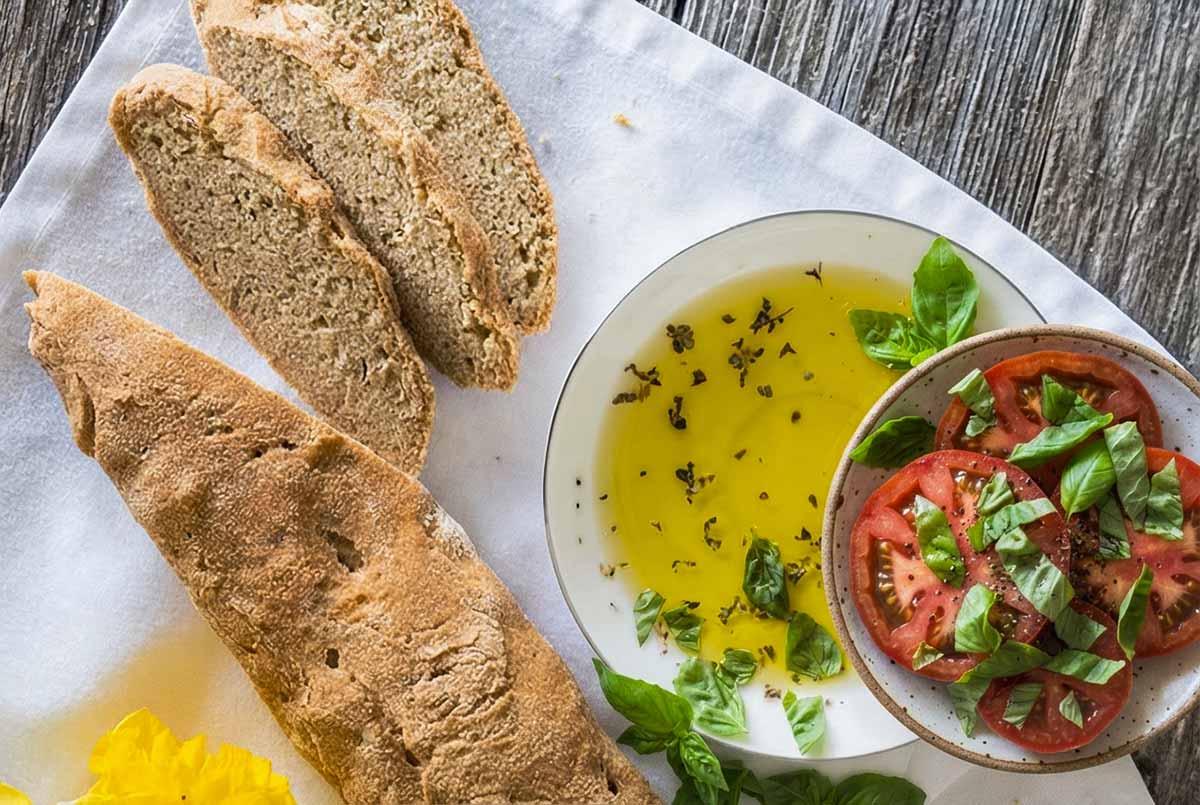 Rustic Gluten-Free Ciabatta Bread with a Crisp Crust with a side of olive oil and sliced tomatoes
