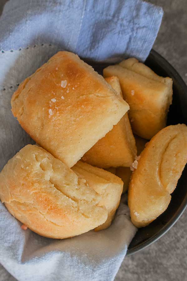 top view of 5 gluten free rolls in a black bowl