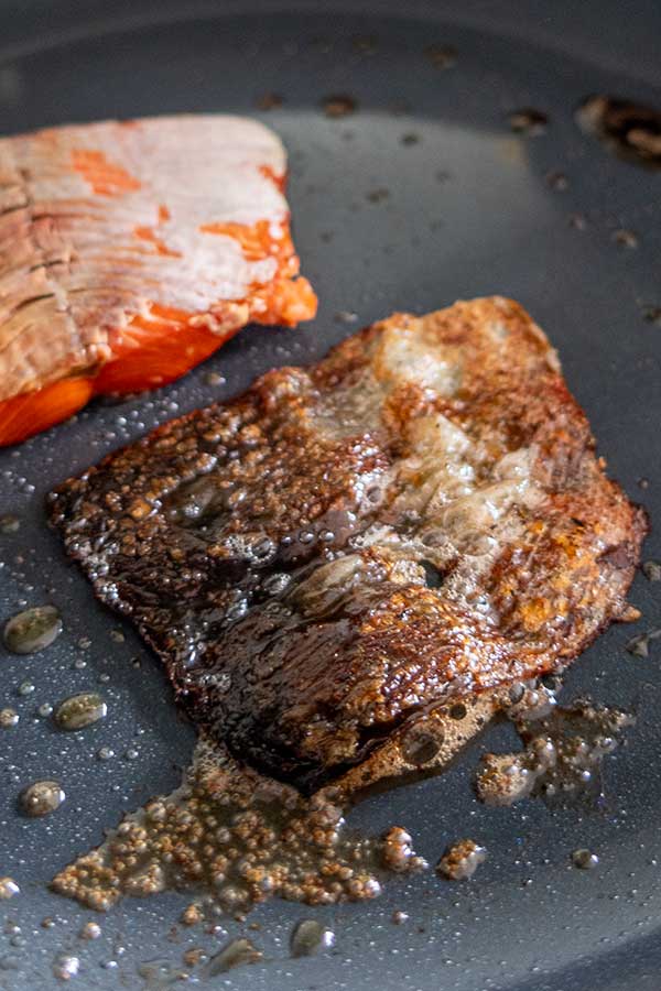 smoked salmon skin cooking in a skillet with salmon