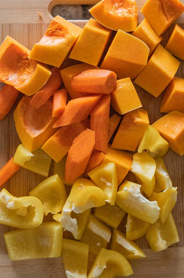 chopped butternut squash, carrots and bell peppers on a cutting board