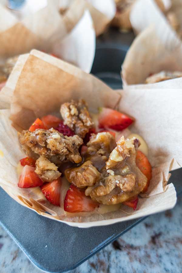 muffin batter topped with strawberries and pecan topping