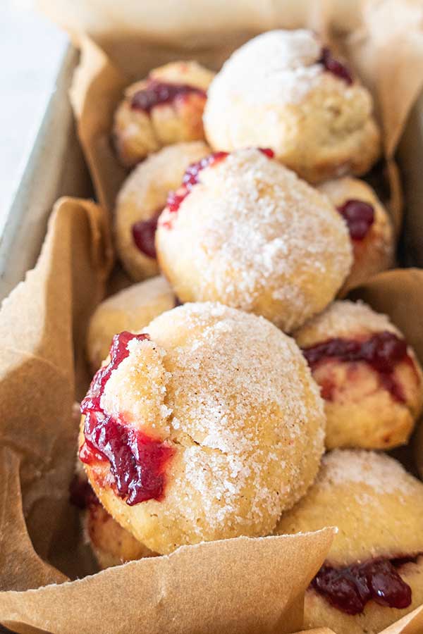 gluten free baked jelly donuts in a pan lined with paper