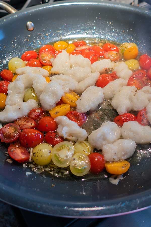 gnocchi and cherry tomatoes cooking in a pan with olive oil