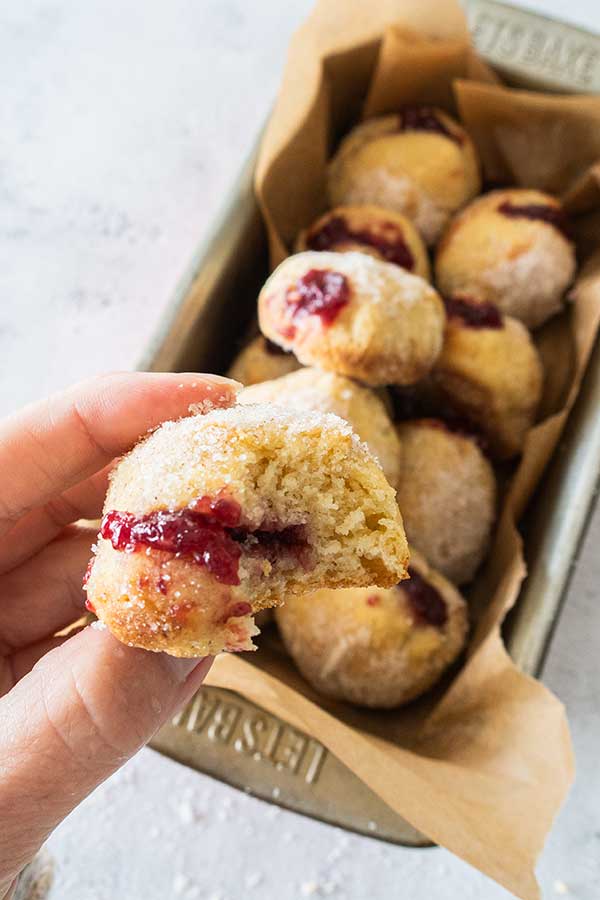 holdinding a siced jelly donut showing strawberry jam