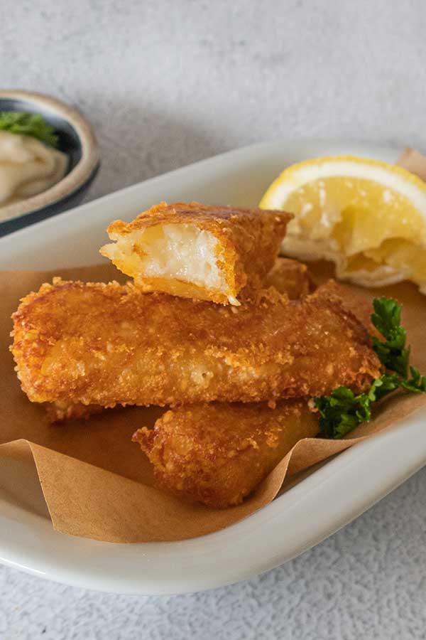 potato sesame cheese sticks on a plate with lemon wedge