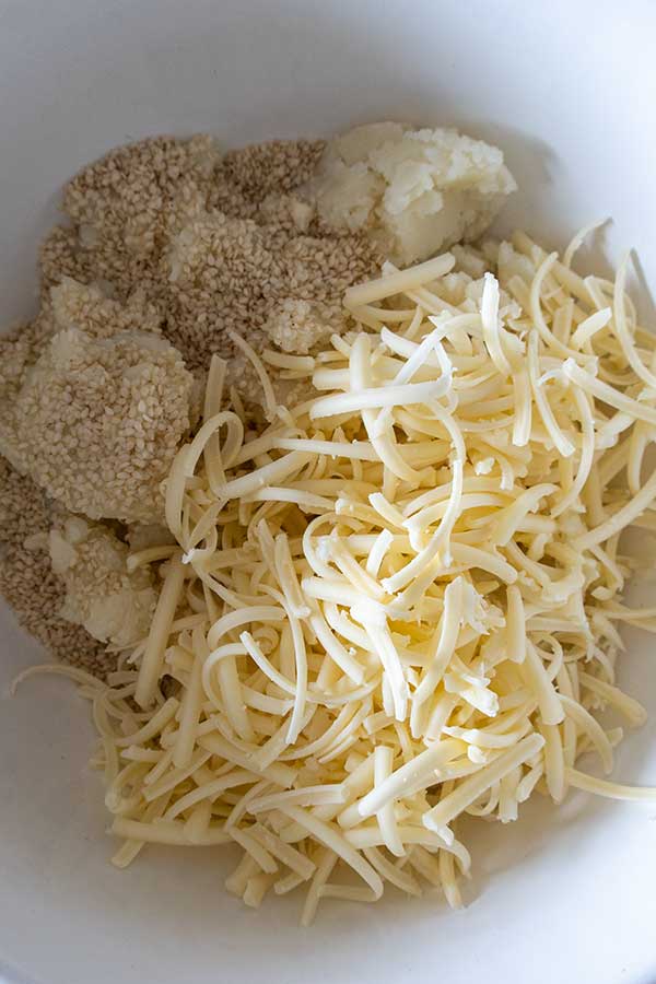 mashed potatoes, cheese, and sesame seeds in a bowl