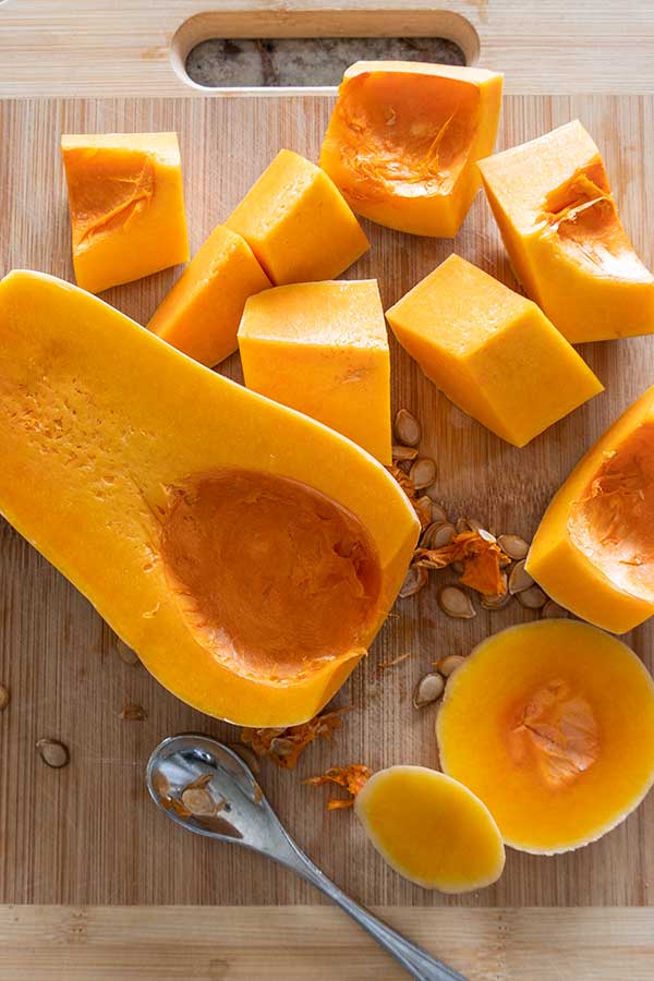 butternut squash chopped into large pieces on a cutting board