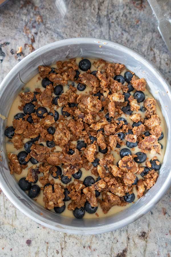 cake batter with blueberries and walnut topping in a cake pan