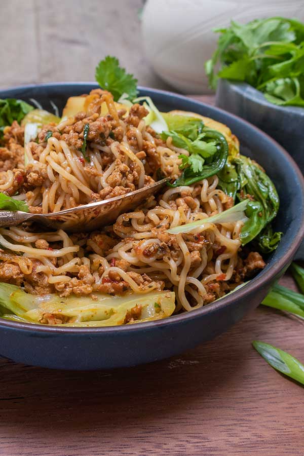 close up sambal pork noodles with bok choy