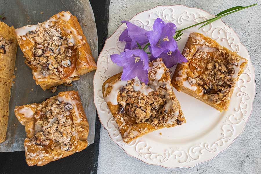 Two apricot Danish coffee cake pieces on a plate, garnished with a purple flower
