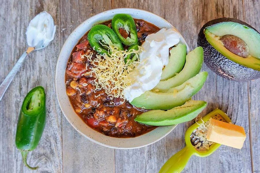 black bean chili topped with avocado and sour cream in a bowl