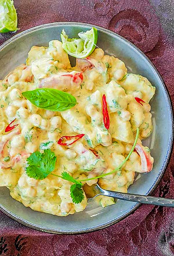 curried potato salad topped with basil and lime wedge in a bowl