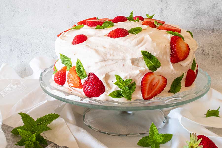 strawberry icebox cake decorated with strawberries on a cake platter