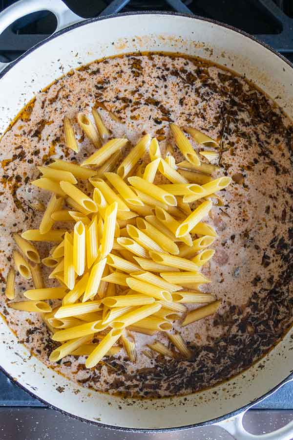 sauce topped with uncooked pasta in a skillet