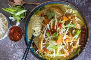 top view of Malaysian noodle soup with chicken and toppings