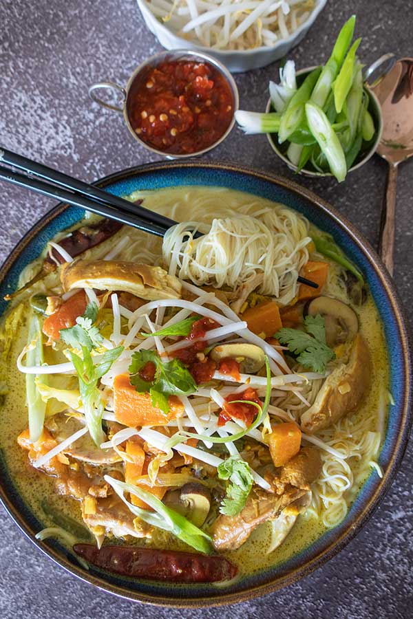 top view of Malaysian noodle soup with chicken and toppings