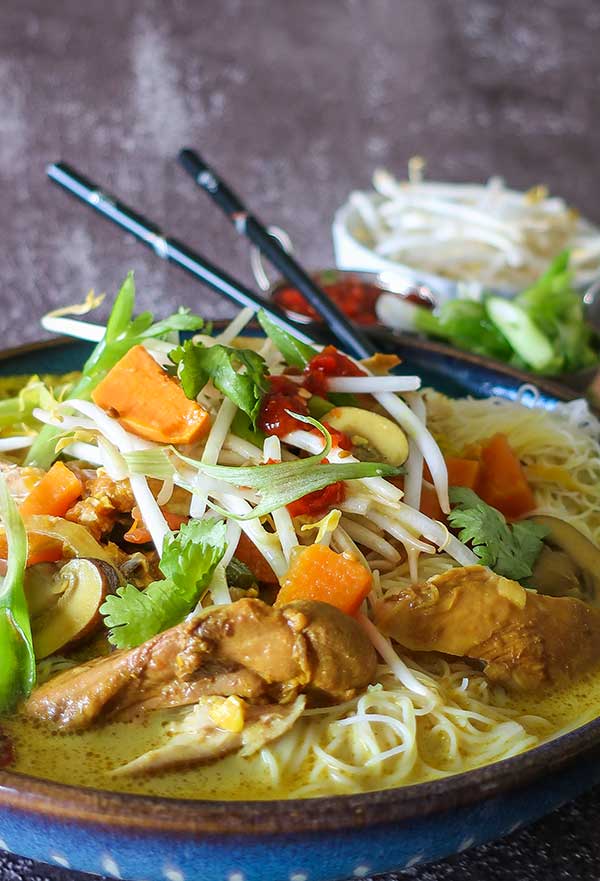 laksa soup with toppings in a bowl with chopsticks