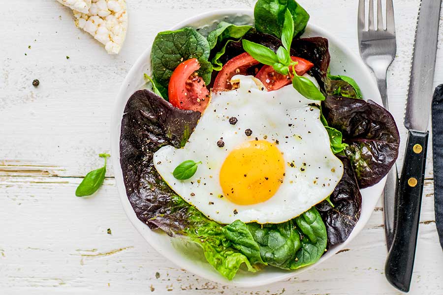 salad topped with poached egg on a plate