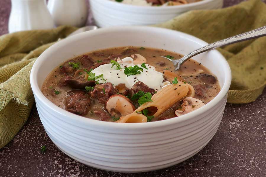 bowl of beef stroganoff soup topped with sour cream