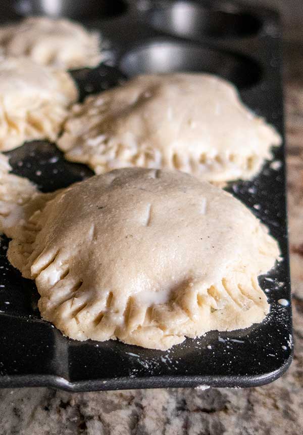 uncooked mini meat pies in a muffin pan