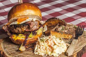 burger in a bun and salad on a board