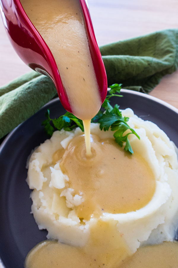 pouring gravy over mashed potatoes