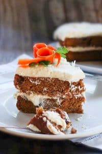 a slice of decorated vegan carrot cake on a plate with a spoon