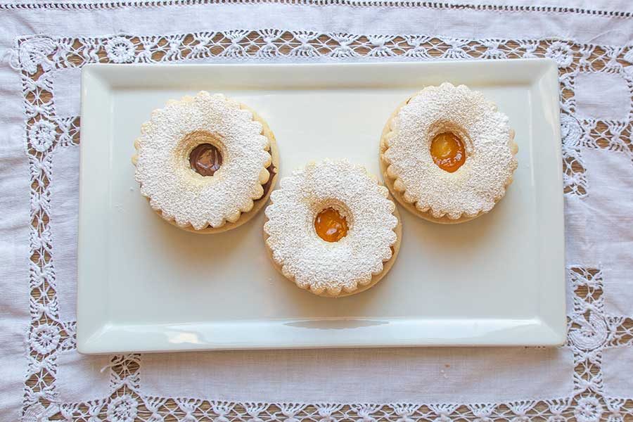 3 linzer Holiday cookies on a dessert plate