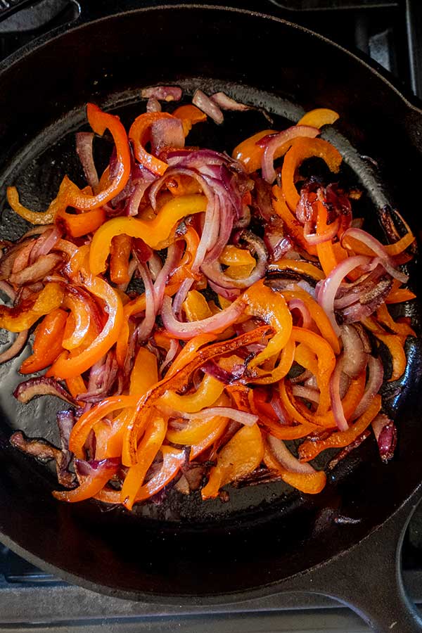 sauteed bell peppers and onions in a cast iron skillet