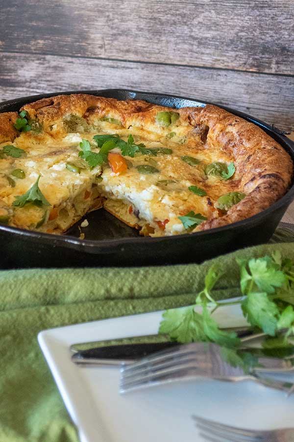 baked savory dutch baby missing a slice in a skillet